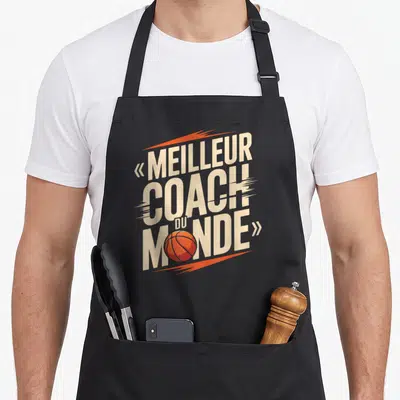 Tablier de cuisine noir avec inscription meilleur coach du monde et ballon de basketball orange stylisé.