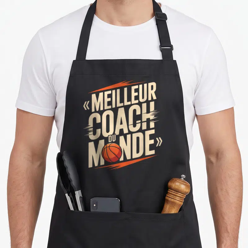 Tablier de cuisine noir avec inscription meilleur coach du monde et ballon de basketball orange stylisé.