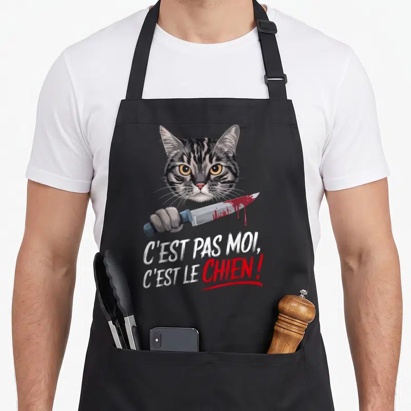 Tablier de cuisine noir illustré d'un chat ténèbreux tenant un couteau ensanglanté sous une citation sarcastique.