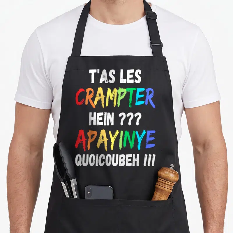 Tablier de cuisine noir avec inscription T'as les crampter hein apayinye quoicoubeh en lettres multicolores style graffiti.