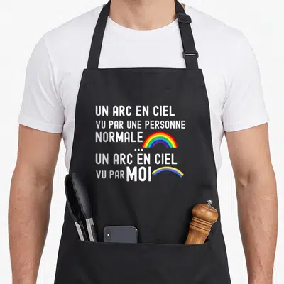 Tablier de cuisine noir avec texte blanc et deux arcs en ciel colorés illustrant la vision d'un daltonien.