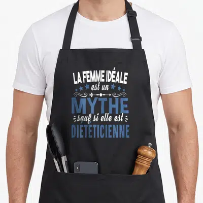 Tablier de cuisine noir avec le texte La femme idéale est un mythe sauf si elle est diététicienne en blanc et bleu.