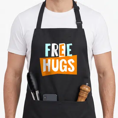 Tablier de cuisine noir avec l'inscription free hugs en lettres orange et bleu cyan sur fond gris uni.