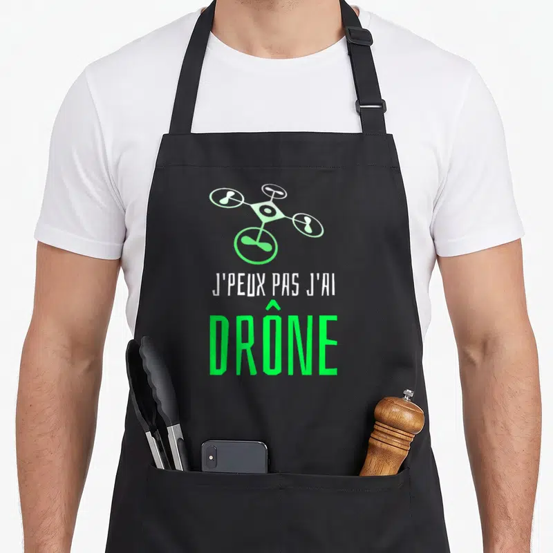 Tablier de cuisine noir avec illustration de drone vert et texte J'peux pas j'ai drône imprimé en blanc et vert fluo.