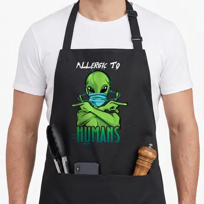 Tablier de cuisine noir avec illustration d'un extraterrestre vert portant un masque bleu et croisant les bras en signe de refus.