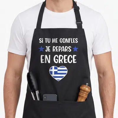 Tablier de cuisine noir avec texte blanc Si tu me gonfles je repars en Grece et un cœur aux couleurs du drapeau grec.