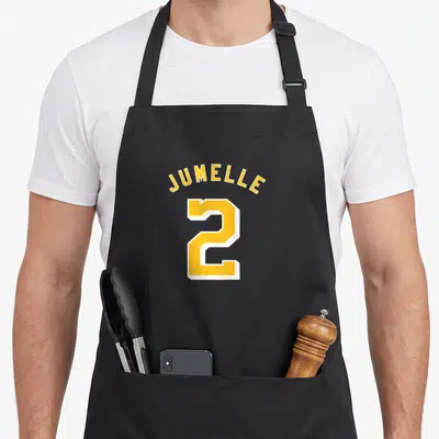 Tablier de cuisine noir avec l'inscription Jumelle 2 en maillot sportif jaune et blanc.