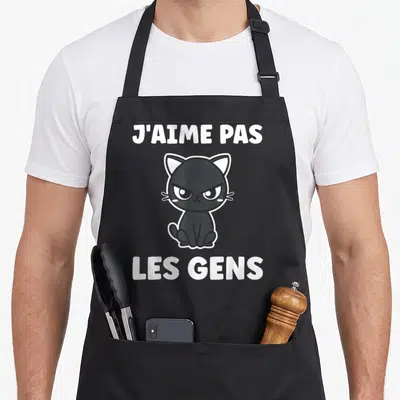 Tablier de cuisine noir avec illustration d'un chat grognon et le texte j'aime pas les gens en blanc.