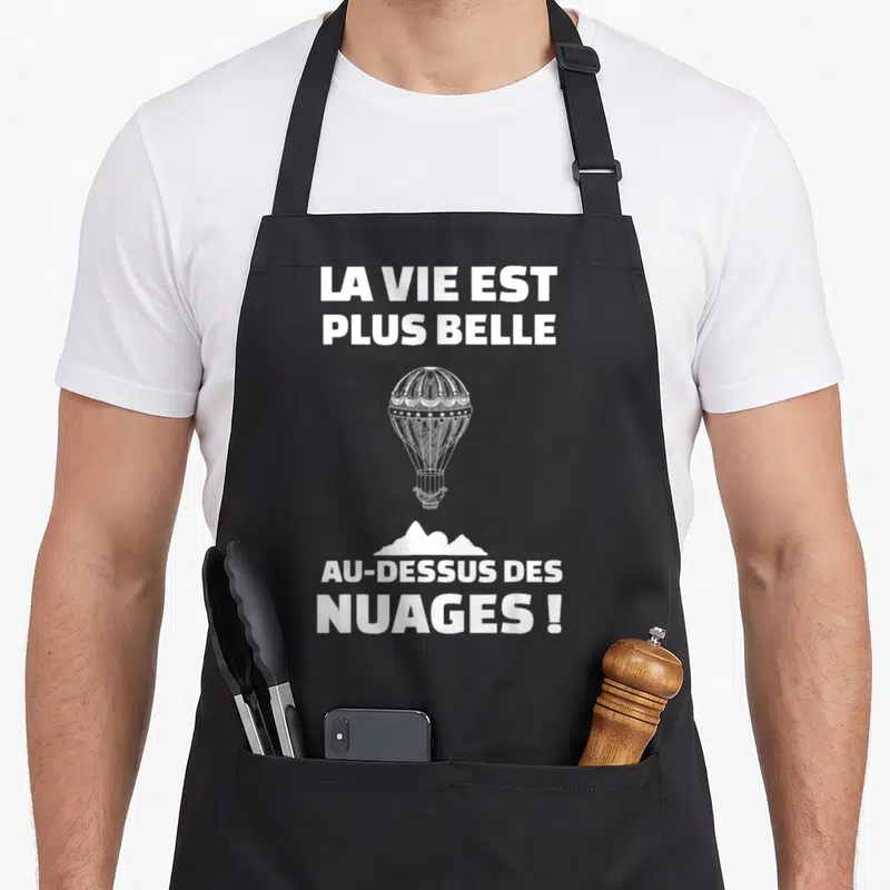 Tablier de cuisine noir avec une montgolfière blanche et l'inscription La vie est plus belle au-dessus des nuages.