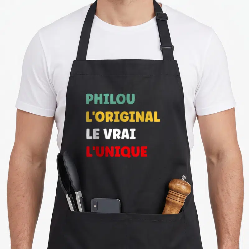 Tablier de cuisine noir avec les mots Philou l'original le vrai l'unique imprimés en couleurs vives.