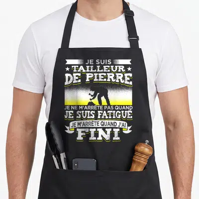 Tablier de cuisine noir orné d'une silhouette taillant la pierre et du texte je suis tailleur de pierre en blanc et jaune.