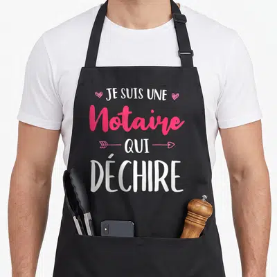 Tablier de cuisine noir avec le texte Je suis une notaire qui déchire en rose et blanc, orné de petits cœurs et d'une flèche.