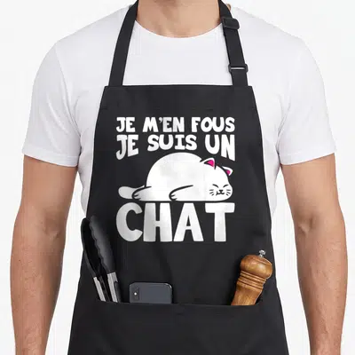 Tablier de cuisine noir avec illustration d'un chat blanc dormant et texte en lettres blanches.