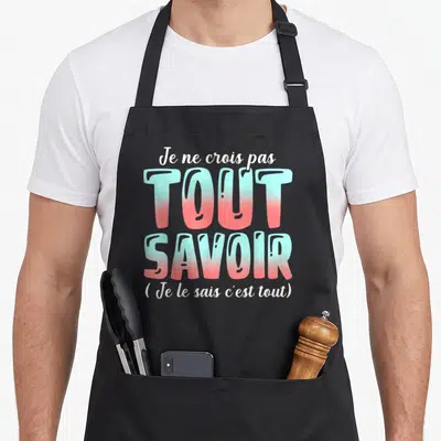 Tablier de cuisine noir avec le texte Je ne crois pas tout savoir en lettres dégradées turquoise et rose.