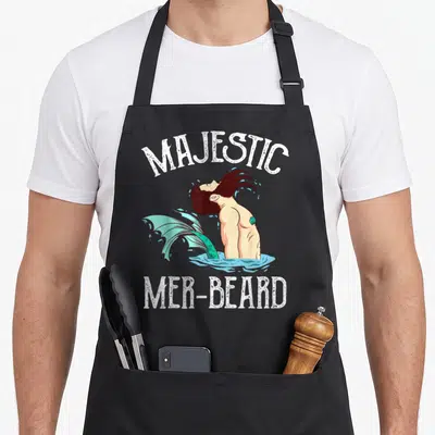 Tablier de cuisine noir avec illustration d'un majestueux mer-beard hipster aux cheveux foncés et queue turquoise émergeant de l'eau.
