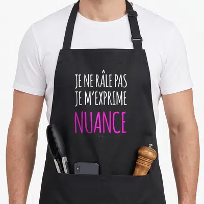 Tablier de cuisine noir avec l'inscription Je ne râle pas je m'exprime nuance en lettres blanches et roses.
