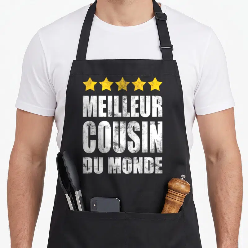 Tablier de cuisine noir avec cinq étoiles jaunes et texte blanc Meilleur Cousin Du Monde en typographie usée.