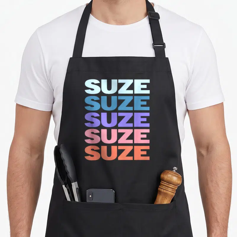 Tablier de cuisine noir avec le mot SUZE répété cinq fois en lettres majuscules colorées de bleu à orange.