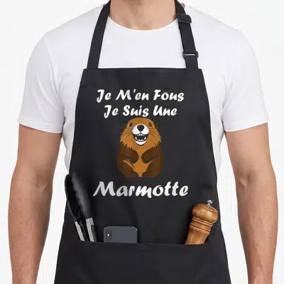Tablier de cuisine noir avec illustration marron d'une marmotte souriante et texte blanc Je m'en fous je suis une Marmotte.