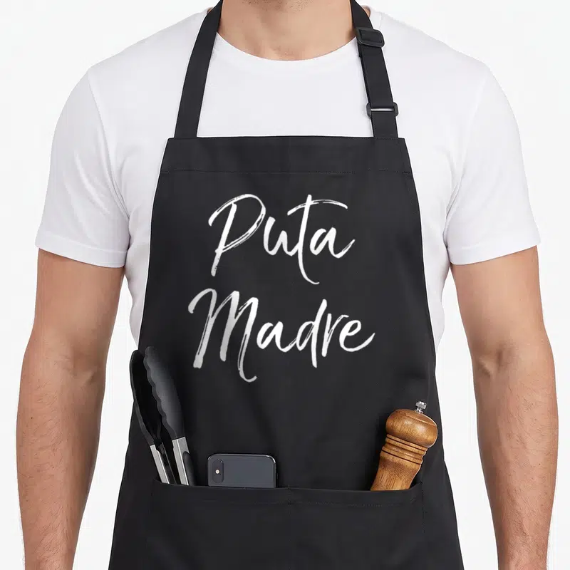 Tablier de cuisine noir avec l'expression Puta Madre écrite en calligraphie blanche stylisée au centre du vêtement.
