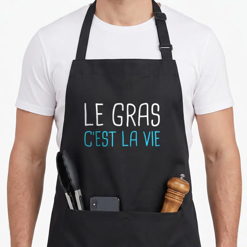 Tablier de cuisine noir avec l'inscription le gras c'est la vie en lettres blanches et bleues au centre.