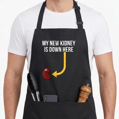 Tablier de cuisine noir avec une illustration de rein rouge bandé et une flèche jaune pointant vers le bas.