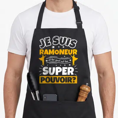 Tablier de cuisine noir avec inscription Je suis ramoneur et toi quel est ton super pouvoir en orange et blanc.