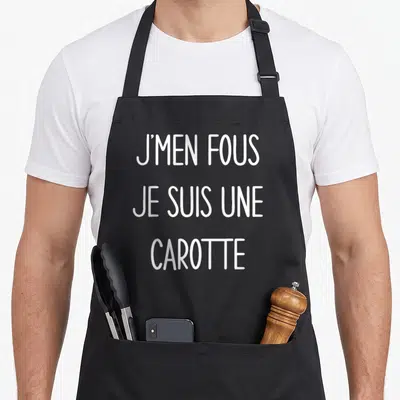 Tablier de cuisine noir avec l'inscription blanche J'Men Fous Je Suis Une Carotte en lettres capitales manuscrites.