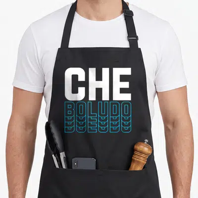 Tablier de cuisine noir avec l'inscription CHE BOLUDO en lettres blanches et bleues stylisées sur le devant.