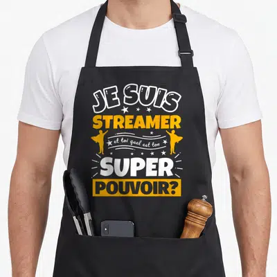 Tablier de cuisine noir avec le texte Je suis streamer et toi quel est ton super pouvoir en blanc et orange.