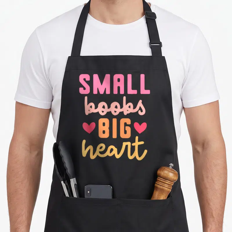 Tablier de cuisine noir avec inscription small boobs big heart en rose et orange flanquée de deux cœurs.