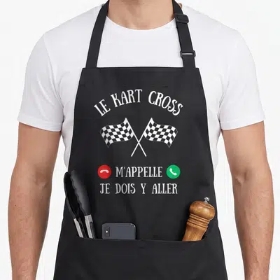 Tablier de cuisine noir avec deux drapeaux à carreaux croisés et texte blanc humoristique.