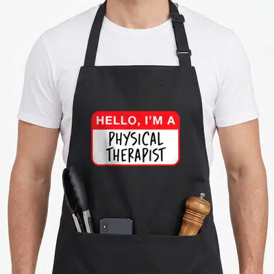 Tablier de cuisine noir avec un autocollant rouge et blanc Hello I'm a Physical Therapist imprimé au centre.