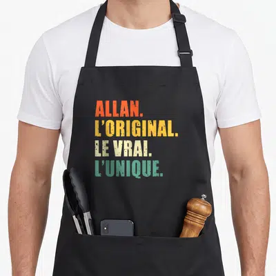 Tablier de cuisine noir avec le texte Allan loriginal le vrai lunique en couleurs vives et typographie délavée.