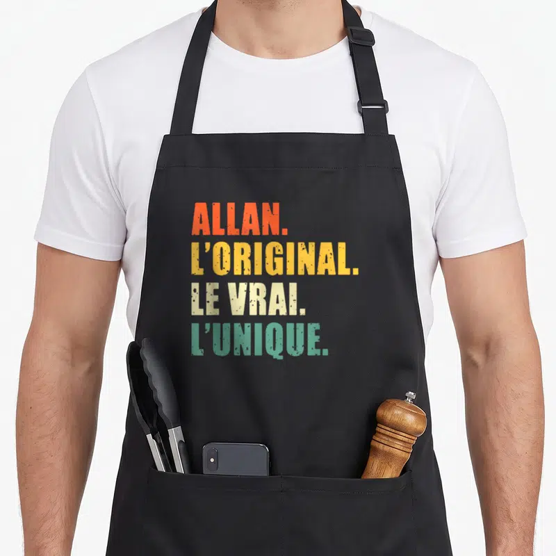 Tablier de cuisine noir avec le texte Allan l'original le vrai l'unique en couleurs vives et typographie délavée.
