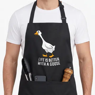 Tablier de cuisine noir avec illustration d'une oie blanche et du texte Life is better with a goose en blanc.