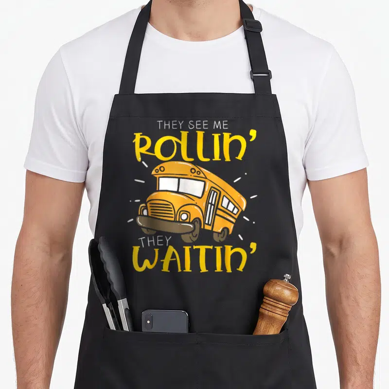 Tablier de cuisine noir avec illustration de car jaune et texte They See Me Rollin They Waitin imprimé en jaune et blanc.