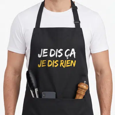 Tablier de cuisine noir avec l'inscription je dis ça je dis rien en typographie blanche et jaune.