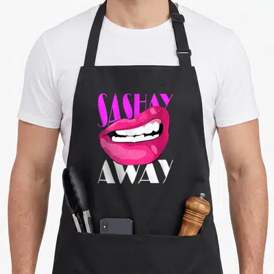 Tablier de cuisine noir avec lèvres roses glossantes et texte sashay away en violet et blanc.
