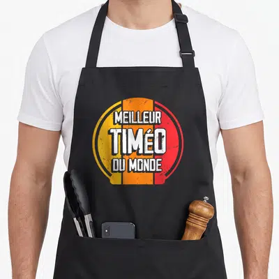 Tablier de cuisine noir avec logo circulaire orange et rouge portant l'inscription Meilleur Timéo du monde.