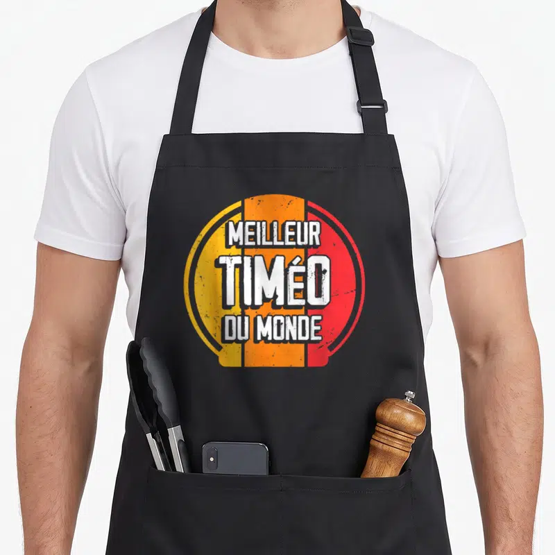 Tablier de cuisine noir avec logo circulaire orange et rouge portant l'inscription Meilleur Timéo du monde.