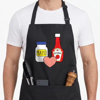 Tablier de cuisine noir avec illustration d'une jarre MAYO, d'une bouteille KETCHUP et d'un cœur rose entre les deux contenants.