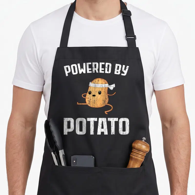Tablier de cuisine noir avec une pomme de terre en course portant un bandeau blanc et le texte printed white.
