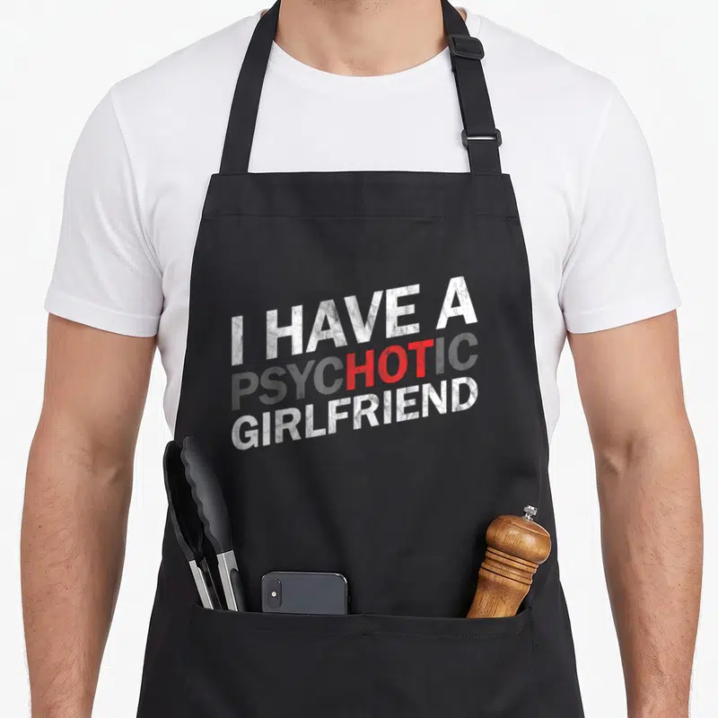 Tablier de cuisine noir avec inscription I Have A Psychotic Girlfriend en blanc et rouge.
