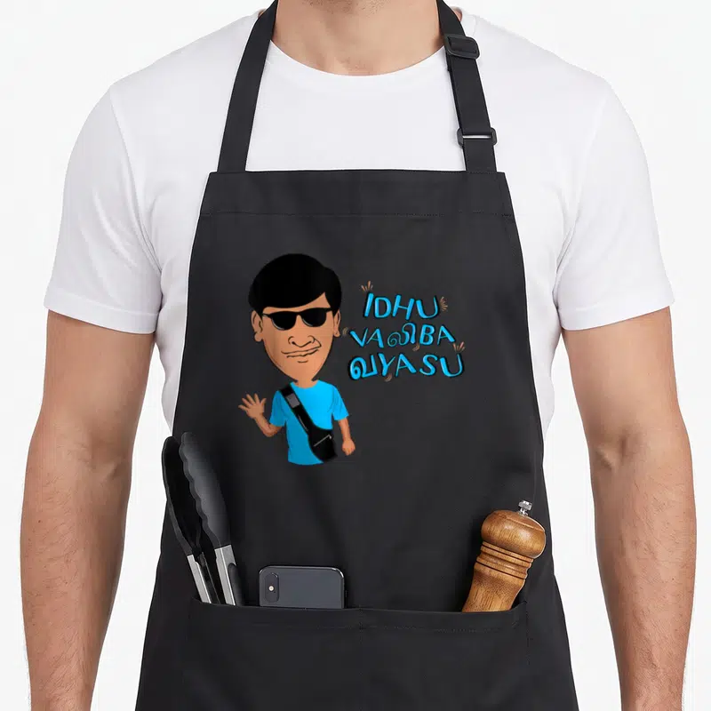 Tablier de cuisine noir avec caricature homme lunettes noires et texte bleu Idhu Valiba Vayasu