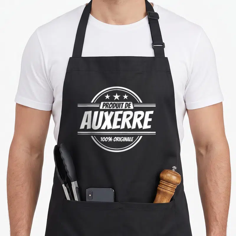 Tablier de cuisine noir avec un logo blanc circulaire affichant Produit de Auxerre 100% Originale et trois étoiles.