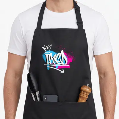 Tablier de cuisine noir avec le prénom Imed en style graffiti blanc sur fonds bleu et rose vif.