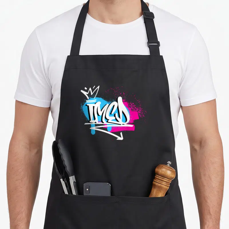 Tablier de cuisine noir avec le prénom Imed en style graffiti blanc sur fonds bleu et rose vif.