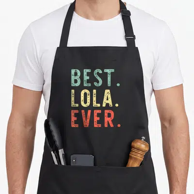 Tablier de cuisine noir avec le texte best lola ever en lettres vintage multicolores.