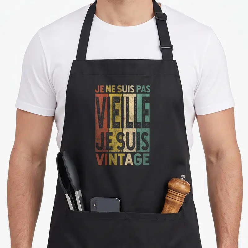 Tablier de cuisine noir avec inscription colorée Je ne suis pas vieille je suis vintage sur fond texturé retro.